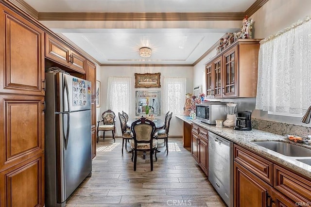 kitchen featuring light stone countertops, sink, hardwood / wood-style floors, appliances with stainless steel finishes, and ornamental molding