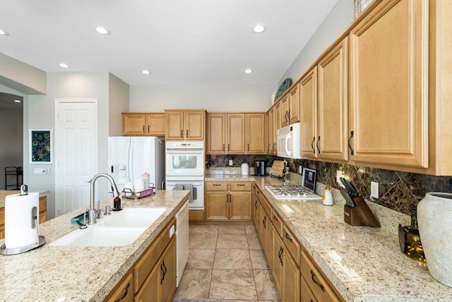 kitchen featuring tasteful backsplash, sink, white appliances, light stone countertops, and light brown cabinets