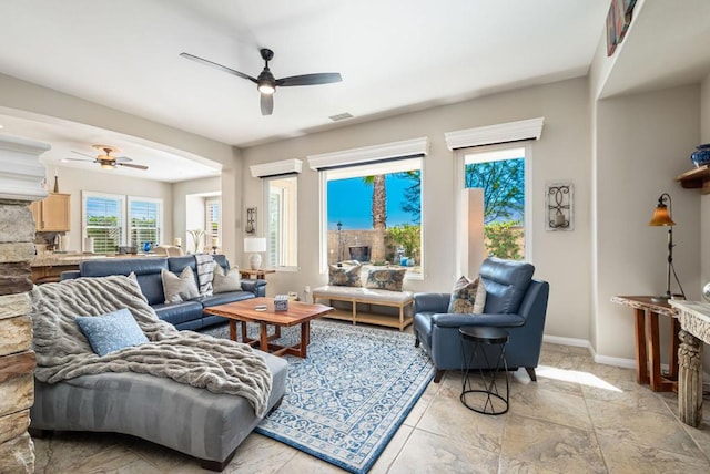 living room with ceiling fan and a stone fireplace