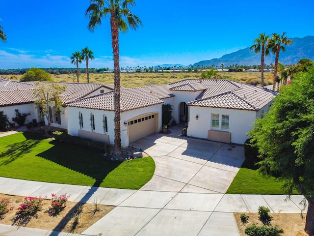 mediterranean / spanish house with a front lawn, a mountain view, and a garage