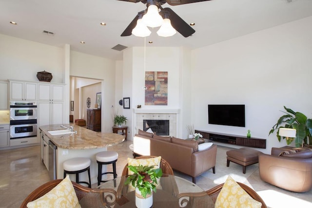 living room with ceiling fan, sink, and a tile fireplace