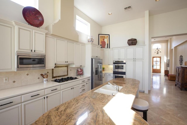 kitchen featuring sink, tasteful backsplash, high vaulted ceiling, a kitchen bar, and appliances with stainless steel finishes