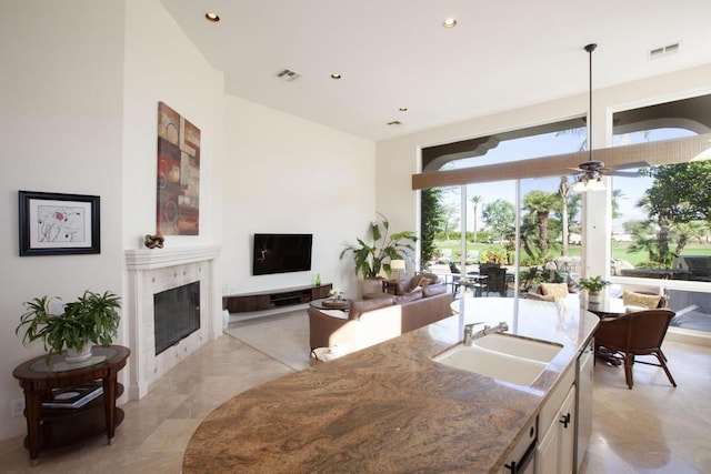 kitchen featuring ceiling fan, sink, a premium fireplace, stainless steel dishwasher, and white cabinets