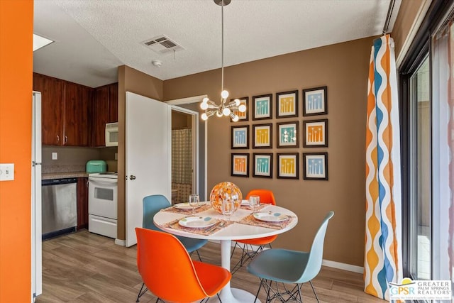 dining area with a chandelier, a textured ceiling, and light hardwood / wood-style floors