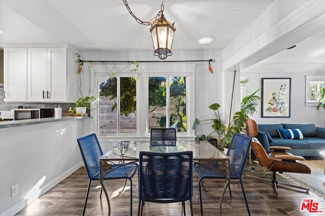 dining room featuring dark hardwood / wood-style flooring, a healthy amount of sunlight, and an inviting chandelier