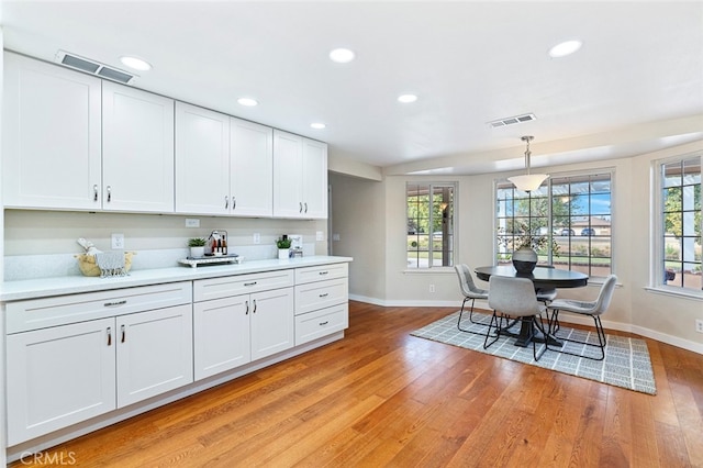 kitchen featuring white cabinets, hanging light fixtures, and light wood-type flooring