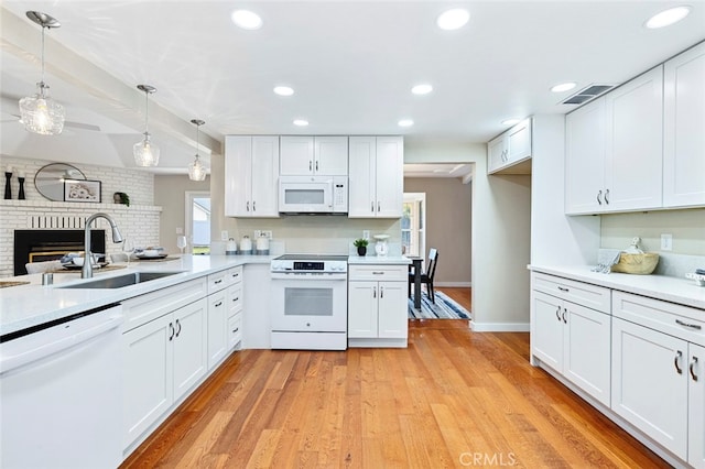 kitchen with white cabinetry, pendant lighting, and white appliances