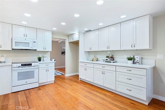 kitchen with white appliances, light hardwood / wood-style floors, and white cabinets