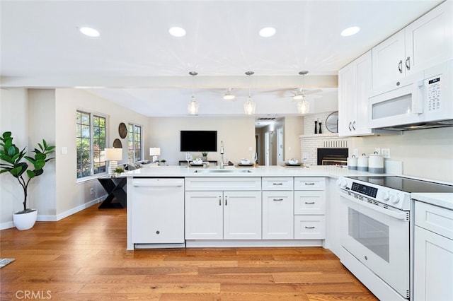 kitchen featuring kitchen peninsula, sink, light wood-type flooring, white cabinets, and white appliances