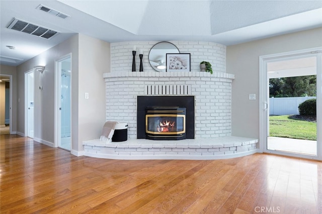 unfurnished living room featuring wood-type flooring, a textured ceiling, and a brick fireplace