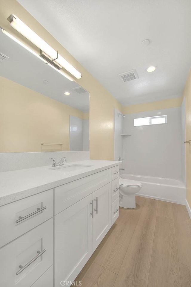full bathroom featuring vanity, hardwood / wood-style flooring, shower / tub combination, and toilet