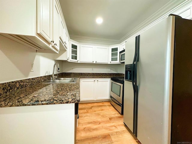 kitchen with white cabinets, sink, ornamental molding, appliances with stainless steel finishes, and light hardwood / wood-style floors