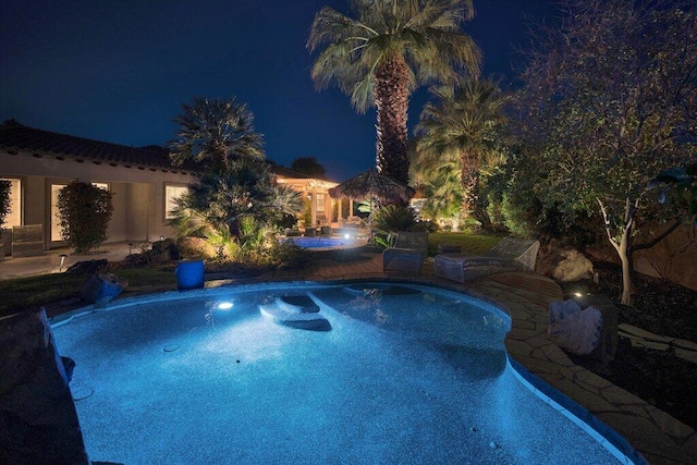 pool at night with a patio area