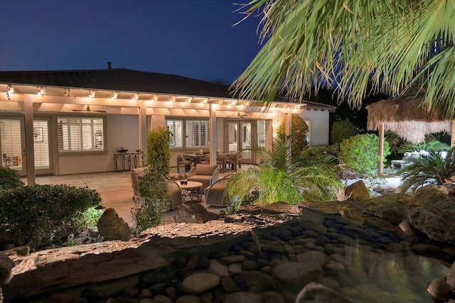 back house at night featuring a patio area and french doors