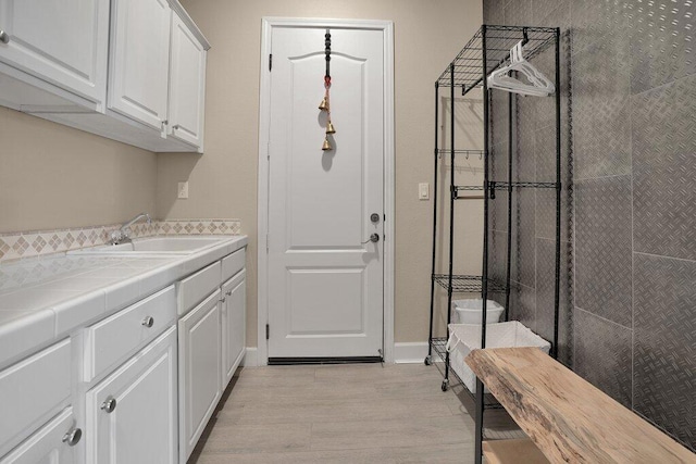 laundry area with light hardwood / wood-style floors and sink