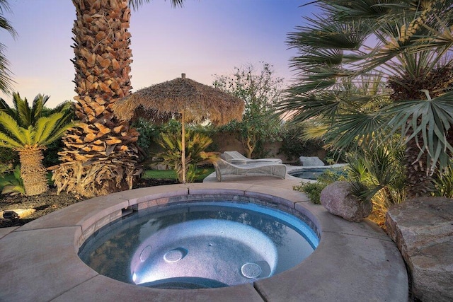 pool at dusk with an in ground hot tub