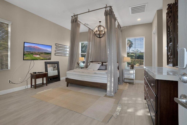 bedroom with a chandelier and light wood-type flooring