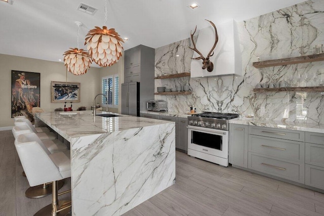 kitchen featuring pendant lighting, sink, a breakfast bar, premium appliances, and light stone countertops