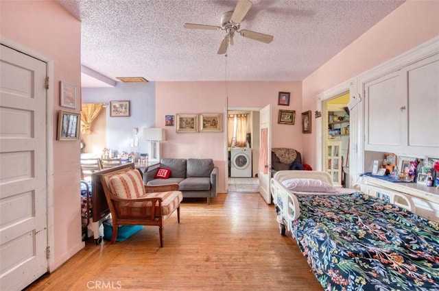 bedroom featuring washer / dryer, a textured ceiling, light hardwood / wood-style floors, and ceiling fan