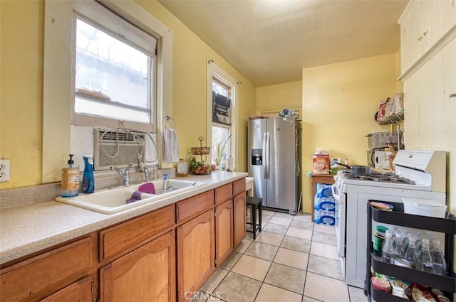 kitchen with sink, stainless steel fridge, white range with gas cooktop, and light tile patterned floors