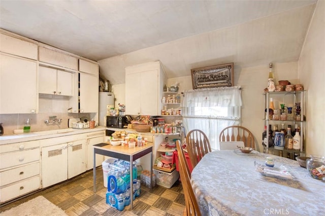 kitchen featuring sink, water heater, and white cabinets