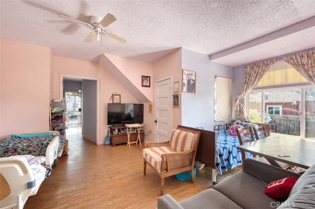 living room featuring ceiling fan, a textured ceiling, and light wood-type flooring