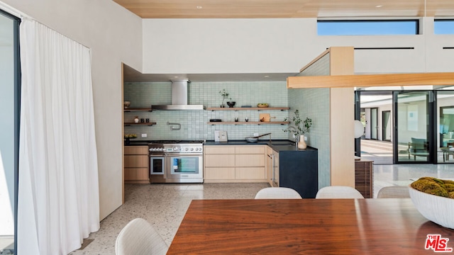 kitchen with decorative backsplash, sink, double oven range, and wall chimney range hood