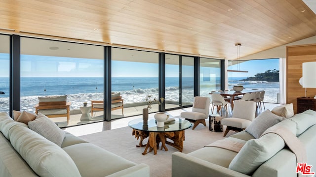 carpeted living room featuring expansive windows, a water view, wood ceiling, and a view of the beach