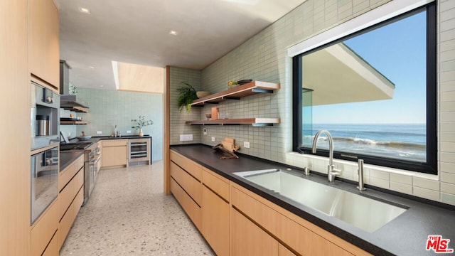 kitchen featuring sink, wine cooler, decorative backsplash, a water view, and appliances with stainless steel finishes