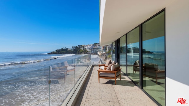 balcony featuring a water view and a beach view