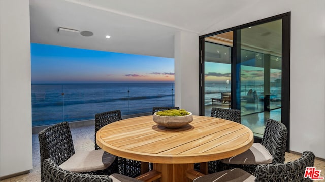 balcony at dusk featuring a water view