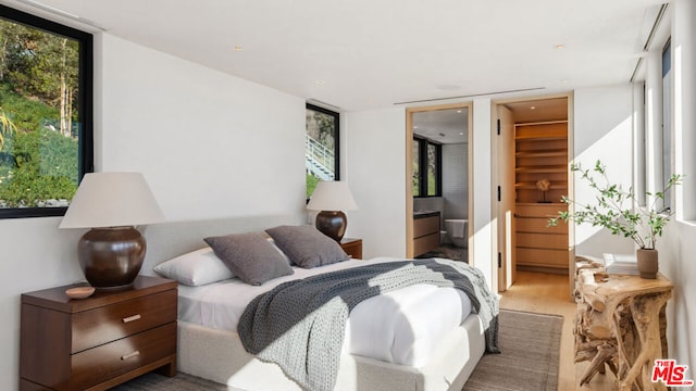 bedroom with a closet, hardwood / wood-style flooring, ensuite bath, and a spacious closet