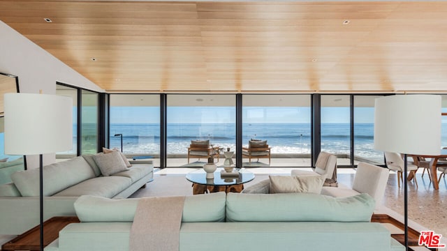 living room featuring a beach view, a water view, plenty of natural light, and floor to ceiling windows