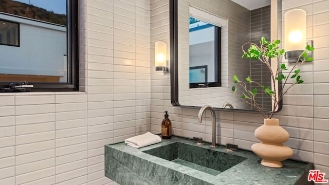 bathroom with tasteful backsplash, tile walls, and sink