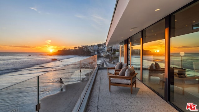 balcony at dusk featuring a water view