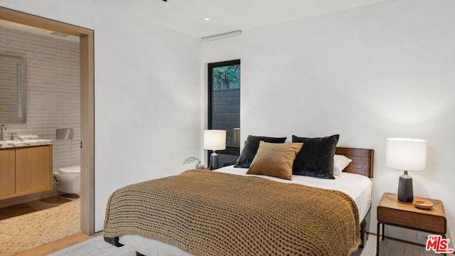 bedroom with ensuite bath and light wood-type flooring