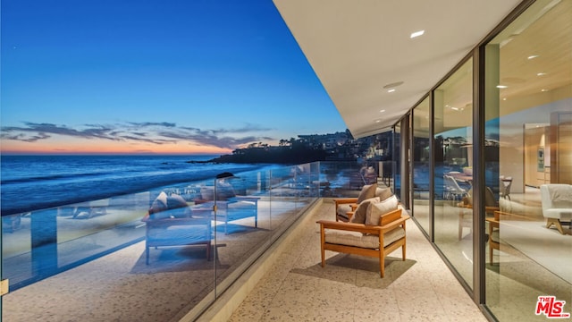 balcony at dusk with a view of the beach and a water view