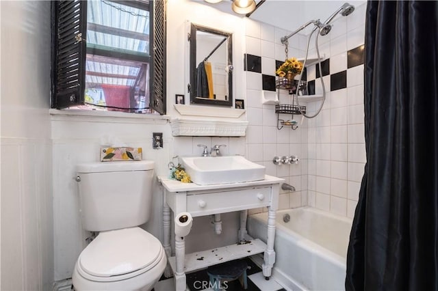 full bathroom with toilet, shower / tub combo with curtain, tile walls, and sink