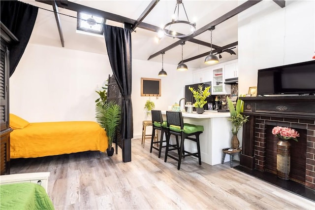 interior space featuring a fireplace, beam ceiling, light wood-type flooring, and a chandelier