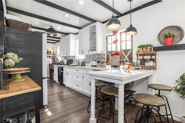 kitchen with a kitchen bar, backsplash, dishwasher, beamed ceiling, and white cabinets