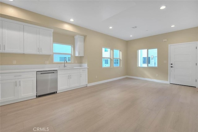 kitchen with sink, white cabinets, stainless steel dishwasher, and light hardwood / wood-style floors