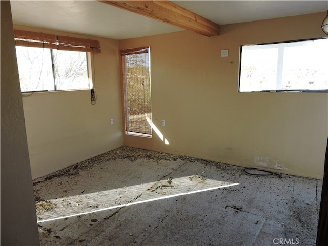 unfurnished room with beamed ceiling