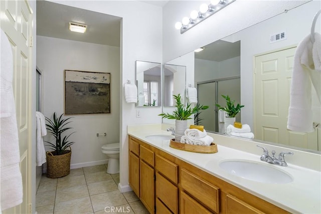 bathroom featuring tile patterned flooring, vanity, toilet, and walk in shower