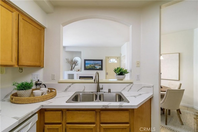 kitchen featuring light stone countertops, white dishwasher, and sink