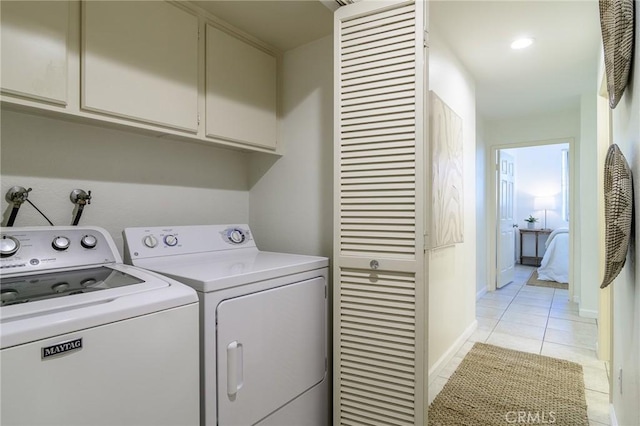 laundry area featuring cabinets, washing machine and dryer, and light tile patterned floors