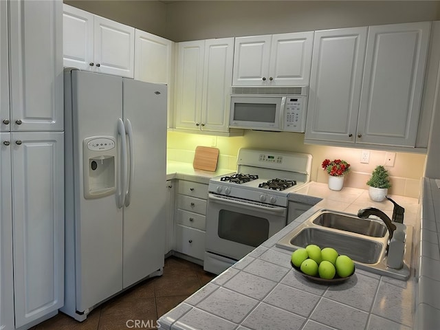 kitchen with backsplash, white appliances, sink, tile countertops, and white cabinetry