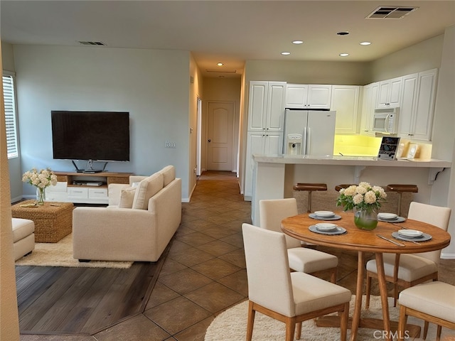 interior space with white cabinetry, a kitchen breakfast bar, kitchen peninsula, white appliances, and dark tile patterned flooring