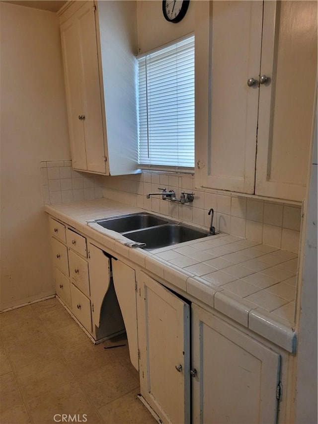 kitchen featuring tile counters, white cabinetry, decorative backsplash, and sink