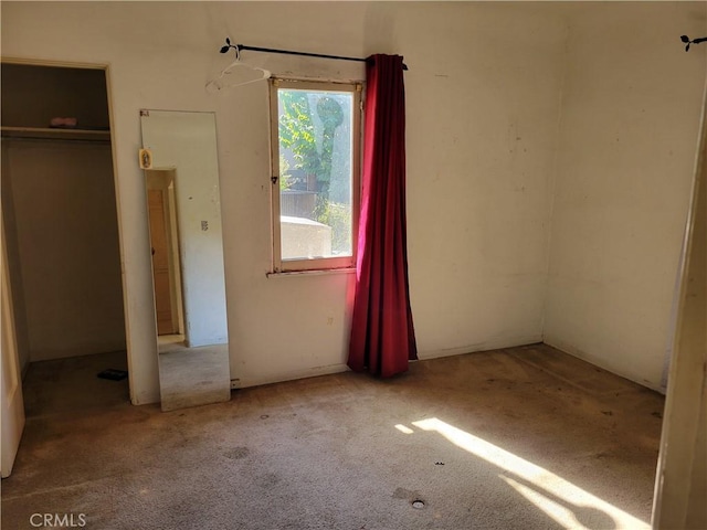 unfurnished bedroom with light colored carpet and a closet