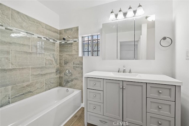 bathroom featuring tiled shower / bath combo, wood-type flooring, and vanity